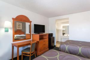 a hotel room with a desk and a bed and a mirror at Redfinn Inn in Fort Pierce