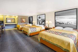 a hotel room with three beds and a desk at Super 8 by Wyndham Fortuna in Fortuna