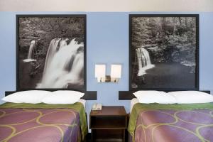 a room with two beds and a picture of a waterfall at Super 8 by Wyndham Jonesboro in Jonesboro