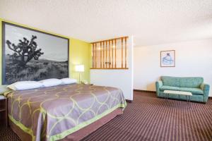 a hotel room with a bed and a chair at Super 8 by Wyndham Kingman in Kingman