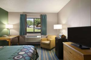 a hotel room with a bed a chair and a television at Super 8 by Wyndham Batesville in Batesville
