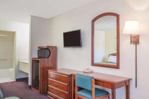 a hotel room with a desk and a mirror at Super 8 by Wyndham Bakersfield/Central in Bakersfield