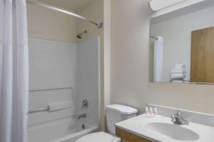 Super 8 by Wyndham Delmont في Delmont: حمام مع حوض ومرحاض ومرآة