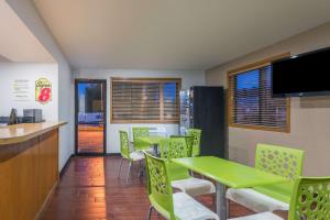 Super 8 by Wyndham Delmont في Delmont: غرفة طعام مع طاولات وكراسي خضراء