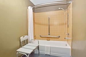 a bathroom with a white tub and a chair at Super 8 by Wyndham Fort Collins in Fort Collins