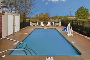 an empty swimming pool with chairs and tables and a fence at Super 8 by Wyndham Greenville in Greenville