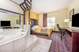 una camera d'albergo con bagno dotato di letto e vasca di Super 8 by Wyndham Bloomington University Area a Bloomington