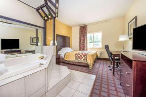 a hotel room with a bathroom with a bed and a tub at Super 8 by Wyndham Bloomington, Indiana in Bloomington