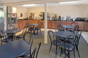 Super 8 by Wyndham Omaha I-80 West في أوماها: غرفة طعام مع طاولات وكراسي ومطبخ