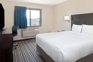 a hotel room with a large bed and a television at Super 8 by Wyndham Omaha I-80 West in Omaha