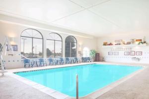 a large swimming pool with blue water in a building at Super 8 by Wyndham West Branch in West Branch