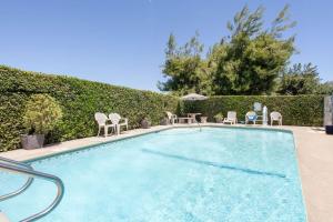 a swimming pool with chairs and an umbrella at Super 8 by Wyndham Selma/Fresno Area in Selma