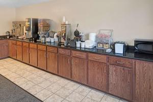 a kitchen with wooden cabinets and a counter top at Super 8 by Wyndham Omaha I-80 West in Omaha