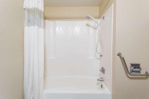 y baño con ducha con cortina blanca. en Super 8 by Wyndham Chadron NE, en Chadron