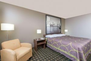 Pokój hotelowy z łóżkiem i krzesłem w obiekcie Super 8 by Wyndham Youngstown/Austintown w mieście Youngstown