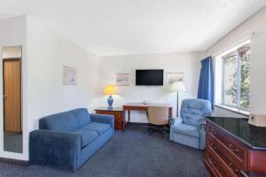a living room with a couch and a chair and a desk at Super 8 by Wyndham Selma/Fresno Area in Selma