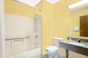 y baño con aseo blanco y lavamanos. en Super 8 by Wyndham Muncie/Ball St. College Area, en Muncie