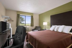 a hotel room with a bed and a desk and a chair at Super 8 by Wyndham Saginaw in Saginaw