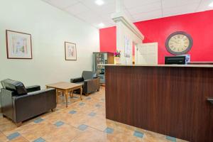 a waiting room with a clock on a red wall at Super 8 by Wyndham Las Cruces University Area in Las Cruces