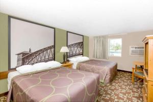 a hotel room with two beds and a balcony at Super 8 by Wyndham Kearney in Kearney