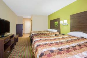 a hotel room with two beds and a flat screen tv at Super 8 by Wyndham Portales in Portales