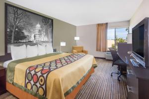 a hotel room with a bed and a flat screen tv at Super 8 by Wyndham Madison South in Madison