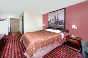 a hotel room with a bed and a picture on the wall at Super 8 by Wyndham Paris IL in Paris