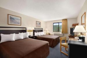 a hotel room with two beds and a desk at Super 8 by Wyndham Williams Lake BC in Williams Lake