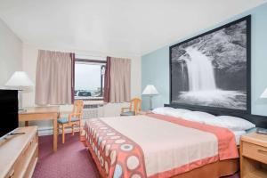 a hotel room with a bed and a desk at Super 8 by Wyndham Tomah Wisconsin in Tomah