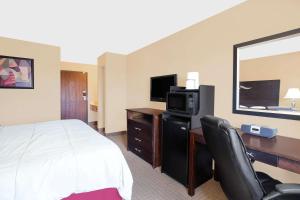 a hotel room with a bed and a desk with a television at Super 8 by Wyndham Sheboygan WI in Sheboygan
