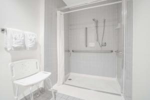 a white bathroom with a shower and a toilet at Super 8 by Wyndham Tomah Wisconsin in Tomah +24 photos