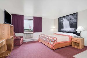 Habitación de hotel con cama y silla en Super 8 by Wyndham Tomah Wisconsin, en Tomah