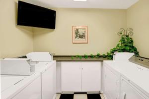 a kitchen with white cabinets and a flat screen tv at Super 8 by Wyndham Independence Kansas City in Independence