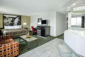 a hotel room with a bed a tub and a television at Super 8 by Wyndham Independence Kansas City in Independence