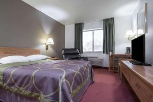 une chambre d'hôtel avec un lit, une chaise et une télévision dans l'établissement Super 8 by Wyndham Fond Du Lac, à Fond du Lac