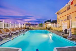 a swimming pool with chairs and a building at Super 8 by Wyndham Independence Kansas City in Independence