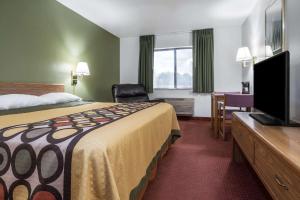 a hotel room with a bed and a flat screen tv at Super 8 by Wyndham Fond Du Lac in Fond du Lac