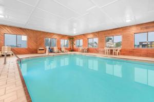 a swimming pool with blue water in a room with windows at Super 8 by Wyndham Ottumwa in Ottumwa