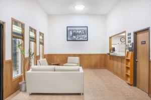 a waiting room with a white couch and chairs at Super 8 by Wyndham Mt Pleasant in Mount Pleasant