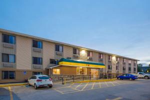 un grand immeuble d'appartements avec des voitures garées dans un parking dans l'établissement Super 8 by Wyndham Iowa City/Coralville, à Coralville