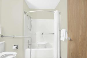 a white bathroom with a shower and a toilet at Super 8 by Wyndham Mt Pleasant in Mount Pleasant +21 photos
