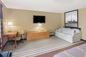 a hotel room with a couch and a desk and a television at Super 8 by Wyndham Knoxville in Knoxville
