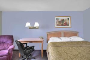 a hotel room with a bed and a desk and a chair at Super 8 by Wyndham Augusta in Augusta