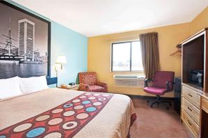 a hotel room with a bed and a chair and a window at Super 8 by Wyndham Baltimore/Essex Area in Essex