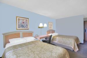 a hotel room with two beds and a desk at Super 8 by Wyndham Augusta in Augusta