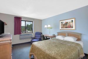 une chambre d'hôtel avec un lit, une chaise et une télévision dans l'établissement Super 8 by Wyndham Augusta, à Augusta
