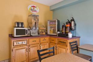 a kitchen with a counter with a microwave and a table at Super 8 by Wyndham Lexington Park/California Area in California