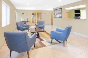 a waiting room with blue chairs and a table at Super 8 by Wyndham East Moline in East Moline
