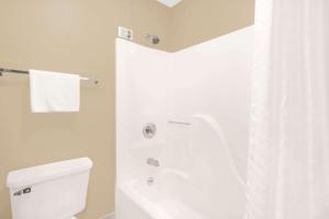 a white bathroom with a shower and a toilet at Super 8 by Wyndham East Moline in East Moline