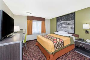 a hotel room with a bed and a flat screen tv at Super 8 by Wyndham Moberly MO in Moberly